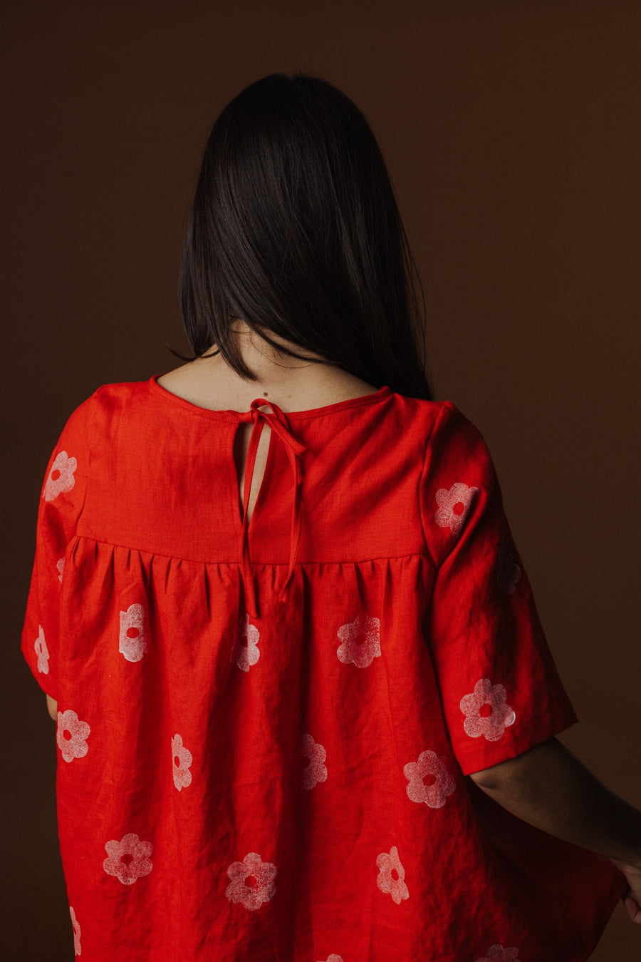 Back detail shot showing the keyhole opening, delicate neck binding, and back tie closure of the red Claire Blouse.