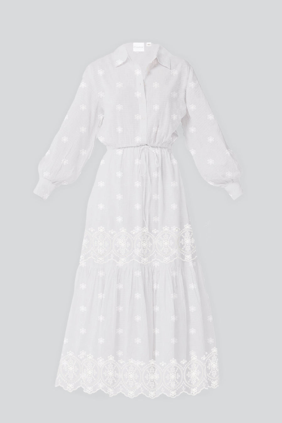 Centered product flat lay studio shot of the Reistor Embroidered Flowy Maxi Tiered Dress in White against a solid grey background, displaying the full front construction, detailed embroidered borders, and cinched drawstring waist.