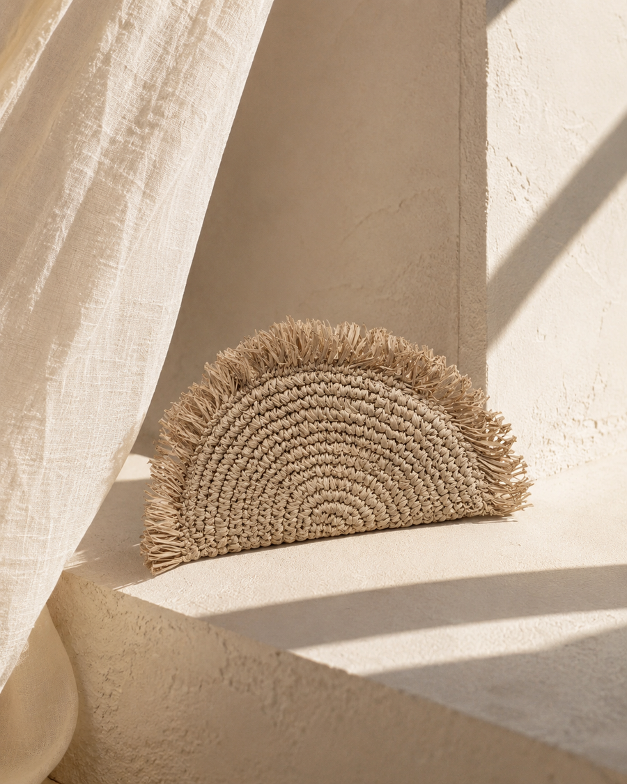 Village Thrive Seagrass Half Moon Clutch handcrafted from natural seagrass with a frayed edge design. 