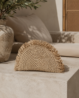 Village Thrive Seagrass Half Moon Clutch handcrafted from natural seagrass with a frayed edge design.