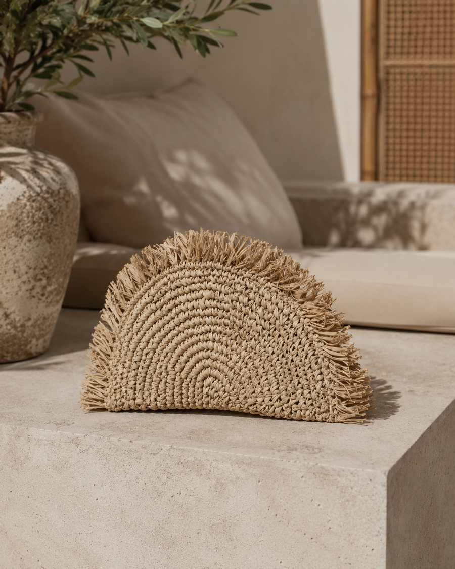 Village Thrive Seagrass Half Moon Clutch handcrafted from natural seagrass with a frayed edge design.