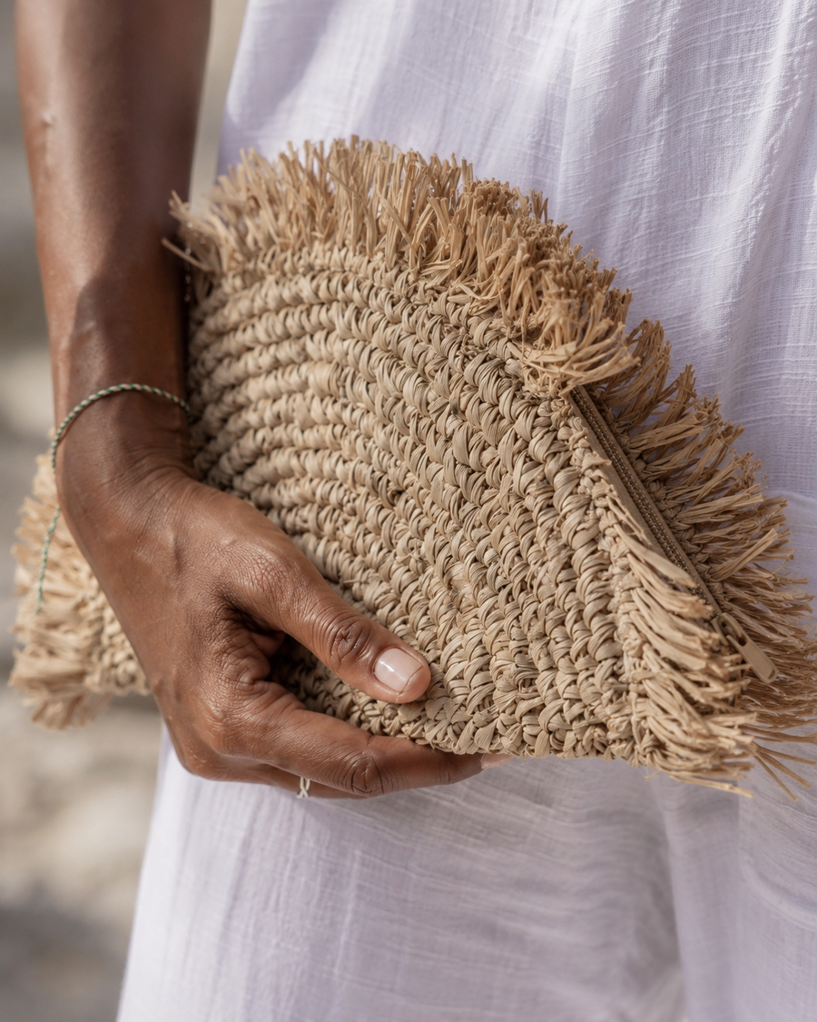 Village Thrive Seagrass Half Moon Clutch handcrafted from natural seagrass with a frayed edge design.