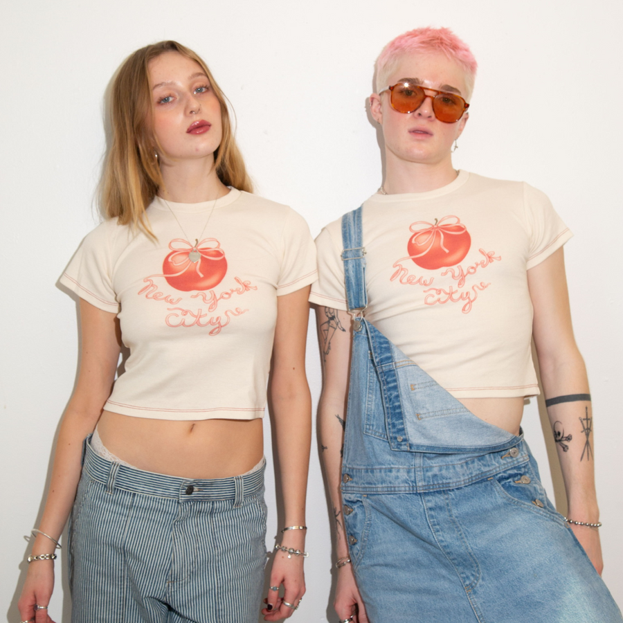 Two models wearing Fruit Face Big Apple baby tees with New York City apple graphic