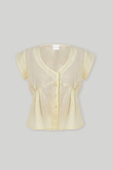 Centered product flat lay shot of Reistor's Deep V Neck Top in Butter Lemon against a plain grey background, clearly displaying the plunging neckline, front buttons, and short cap sleeves.