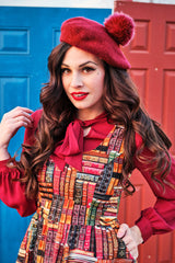 Close-up portrait of model wearing the Retrolicious novelty book print dress with a scoop neck layered over a red long-sleeve bow tie blouse.