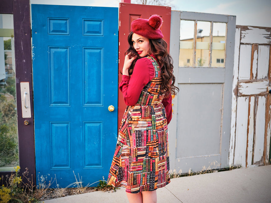 Back view of the Retrolicious teacher style book print A-line dress showing the longer length skirt against a colorful door background.