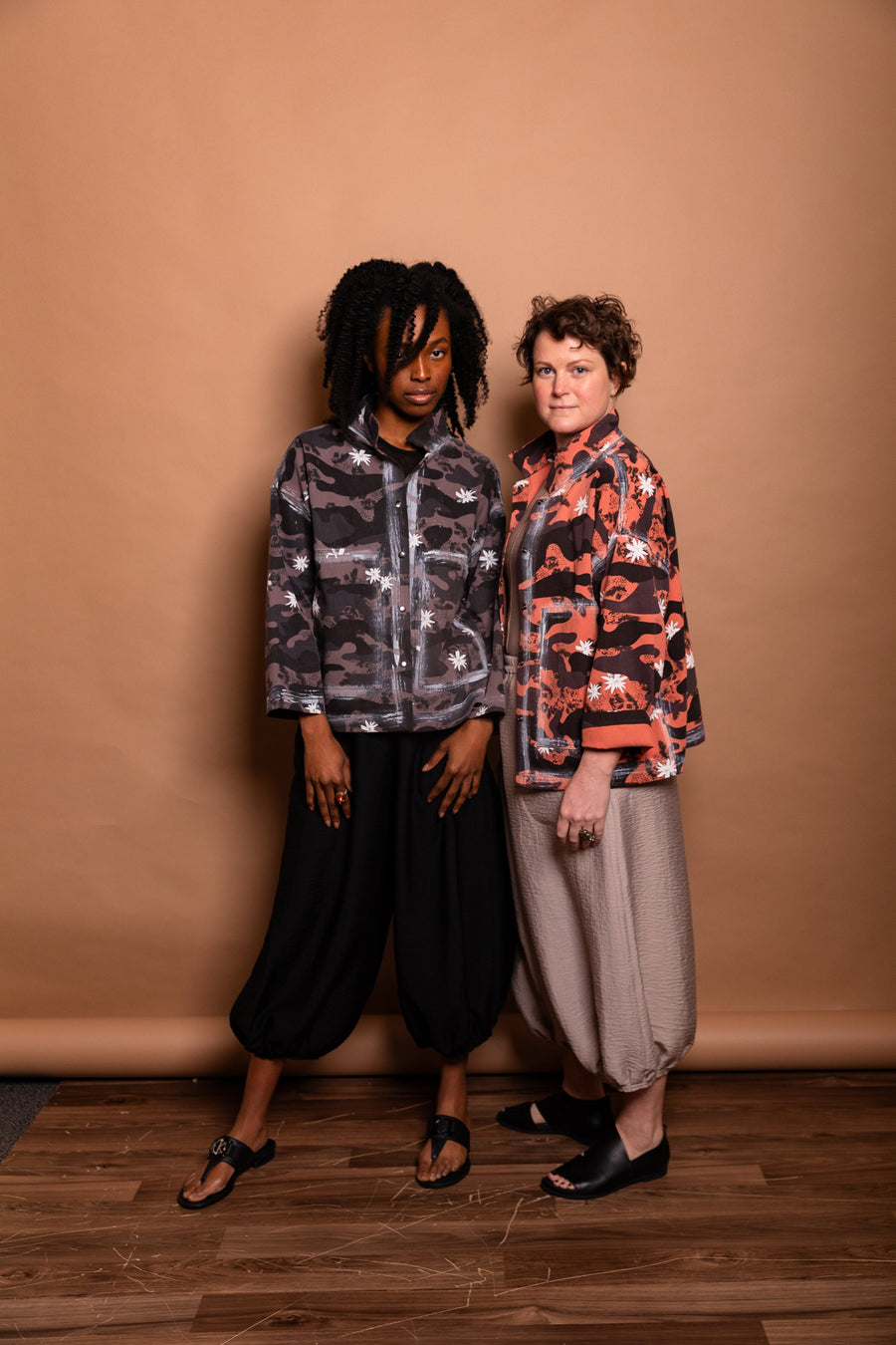 Group studio portrait featuring two models demonstrating both Mushroom grey and Sherbet orange colorways of the Megan-Ilene Studio Jacket side-by-side.  