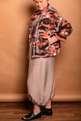 Three-quarter profile shot highlighting the expansive hand-painted patch pockets and wide sleeves on the Sherbet orange Studio Jacket.