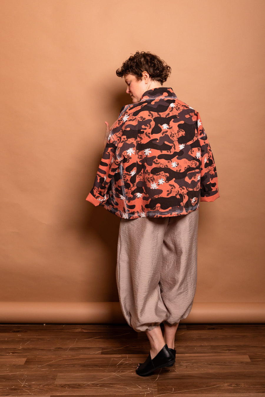 Back view showing the hand-painted white seam architecture and camouflage floral print of the Sherbet Studio Jacket.