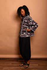 Side view of the model wearing the dark Mushroom Studio Jacket highlighting the 2D white hand-painted outline effect along the pocket and side seams.