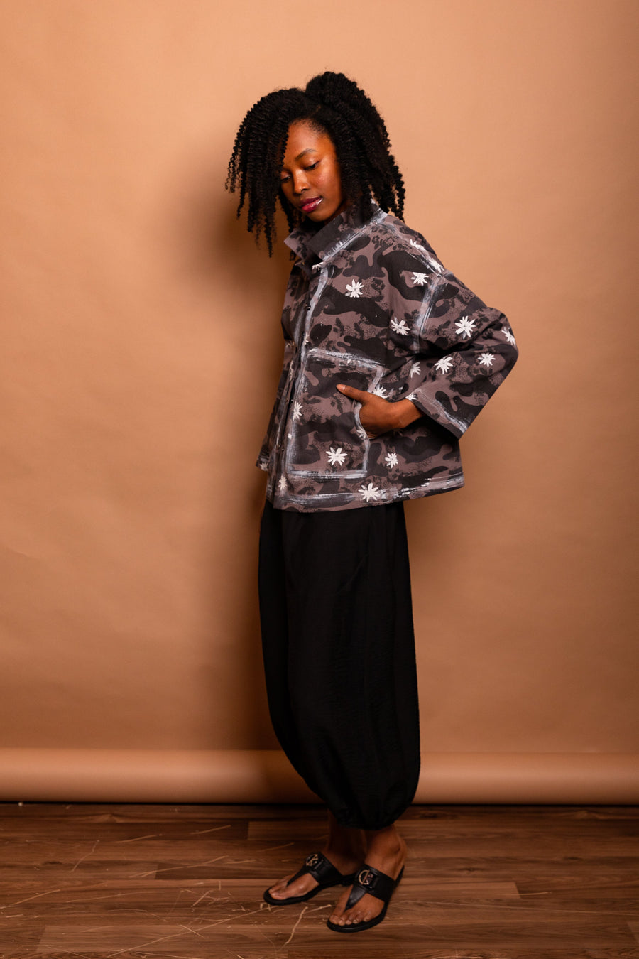 Side view of the model wearing the dark Mushroom Studio Jacket highlighting the 2D white hand-painted outline effect along the pocket and side seams.