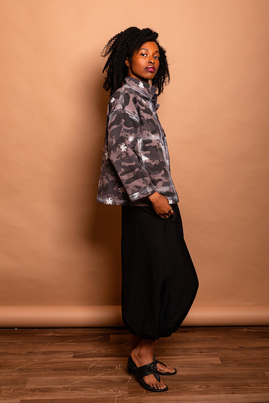 Profile side view of a model wearing the dark Mushroom grey Trompe-l'œil Studio Jacket highlighting sleeve length and boxy cropped cut.