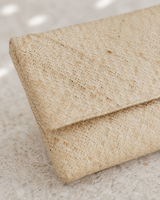 Close-up macro shot showcasing the intricate, tight geometric weave pattern of the natural straw clutch material.
