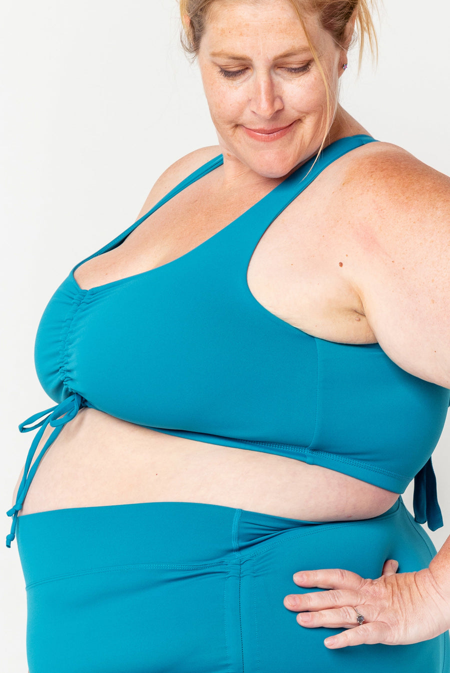 Side profile view highlighting the full underarm and side coverage of the teal Superfit Hero Cinched Bikini Swim Top.