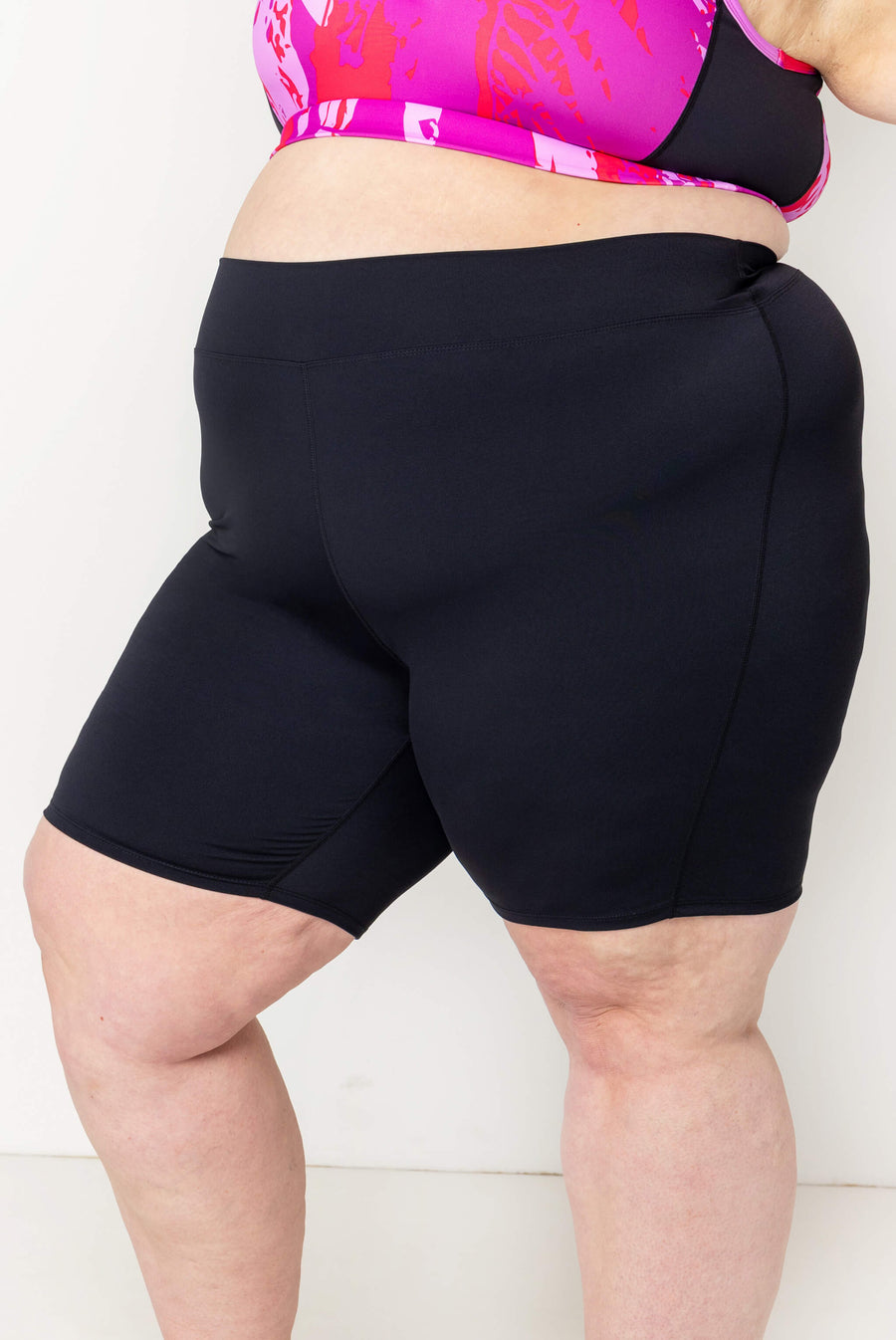 Close-up side-front view highlighting the smooth, curve-hugging compression fit of the black 9-inch swim shorts.
