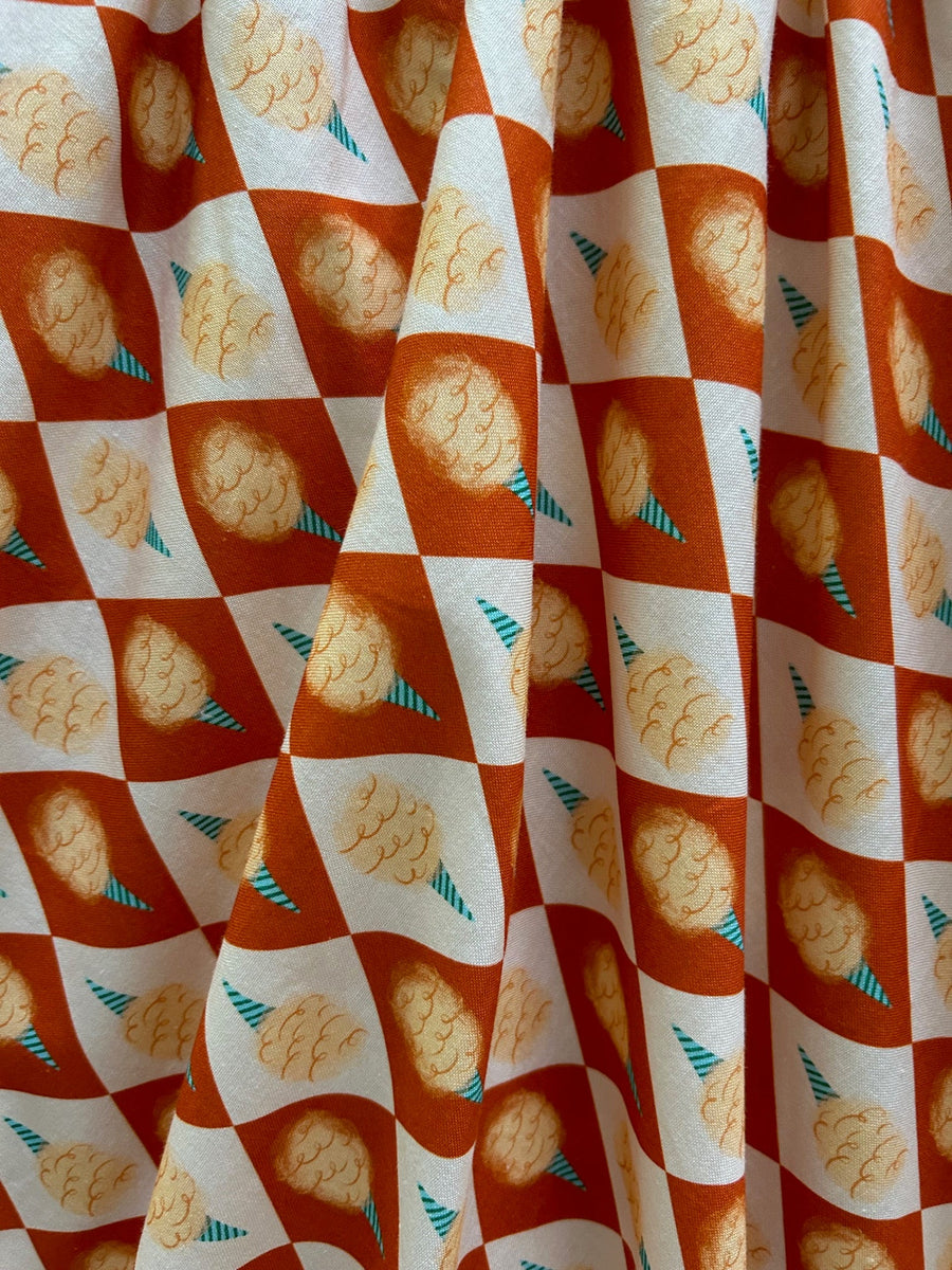 High-resolution detail shot of the 100% cotton fabric featuring a rust orange checkered pattern with cotton candy graphics.