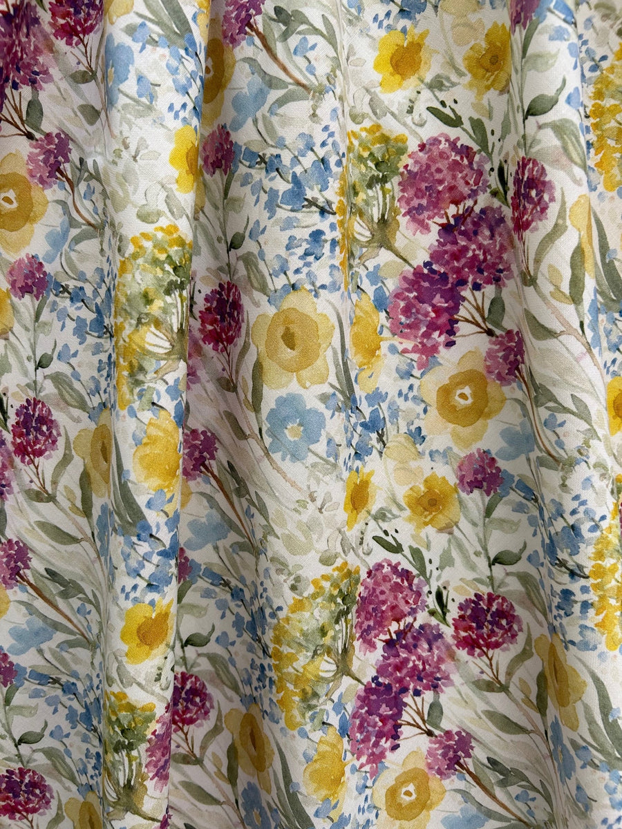 Close-up fabric detail of the Retrolicious Wildflower print showing purple, yellow, and blue floral watercolor illustration on 100% cotton.