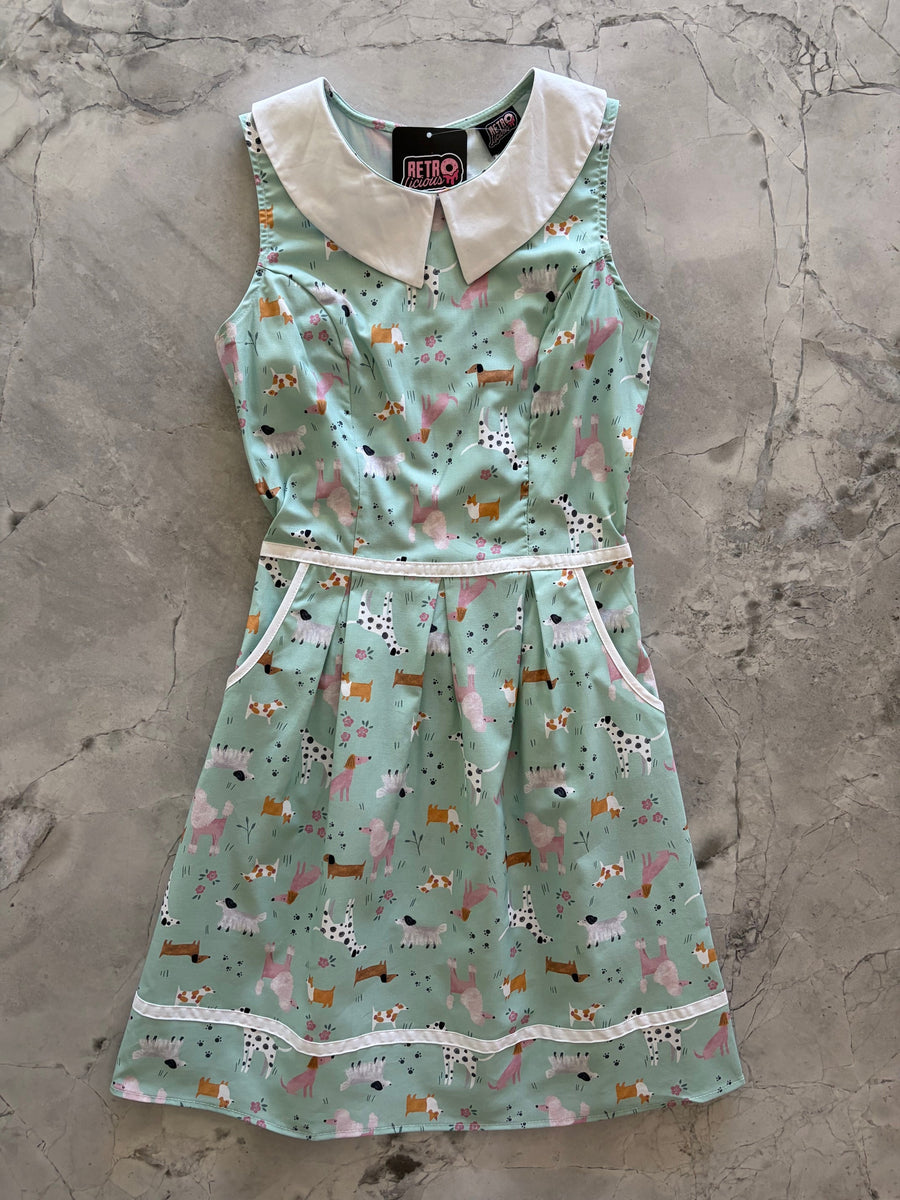 Flat lay product photo of the Retrolicious Dogs Collared Dress on a gray marble background showing the full A-line skirt, white collar, and pocket piping.