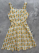 Flat lay product photo of the Retrolicious Pineapple Skater Dress on a gray marble background showing the full A-line skirt and scoop neck.