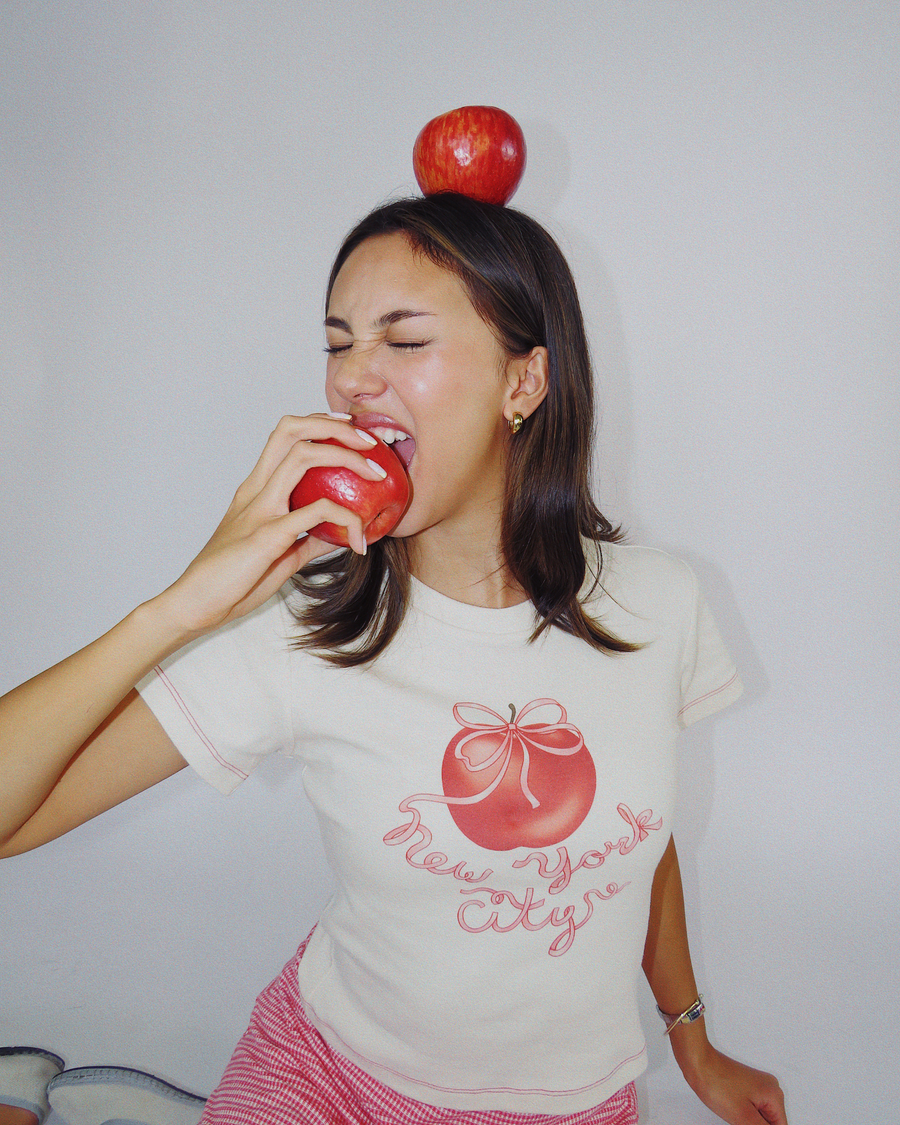 Model wearing Fruit Face Big Apple baby tee with New York City graphic