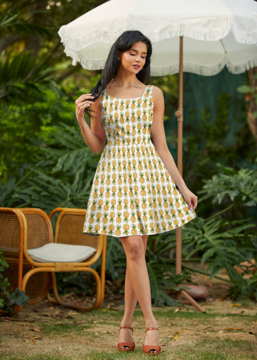Model posing outdoors wearing the Retrolicious Pineapple Skater Dress featuring an all-over watercolor pineapple print and flirty A-line skirt.