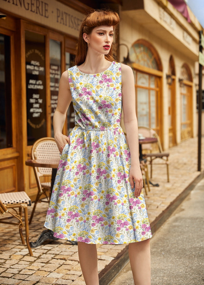 Model posing outside a French cafe wearing the Retrolicious Wildflower vintage 1950s style dress with hands in side pockets.