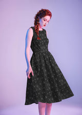 Studio portrait of a model wearing the sleeveless Retrolicious Spiderweb Midi Dress featuring a 1950s high neckline and full swing skirt.