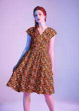 Three-quarter studio portrait highlighting the flared knee-length skirt and cap sleeves of the Greta Dress.