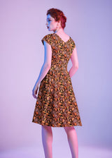 Back view portrait of the model showing the V-back neckline and center back zipper closure of the Greta Dress.