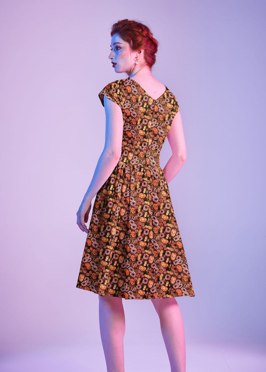 Back view portrait of the model showing the V-back neckline and center back zipper closure of the Greta Dress.