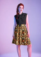 Studio portrait of a model wearing the Retrolicious Cats & Pumpkins A-line Skirt paired with a black bow-tie sleeveless top.