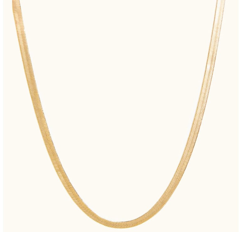 Able A sleek gold herringbone chain necklace by ABLE displayed in a classic curved layout against a clean cream background