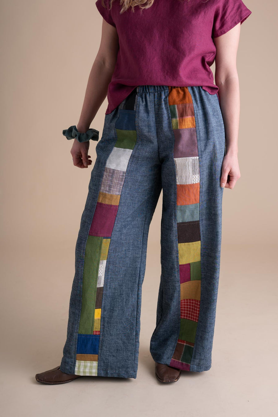 Three-quarter front view of the hemp and organic cotton Joystripe Pants in Indigo Chambray styled with a berry linen top.