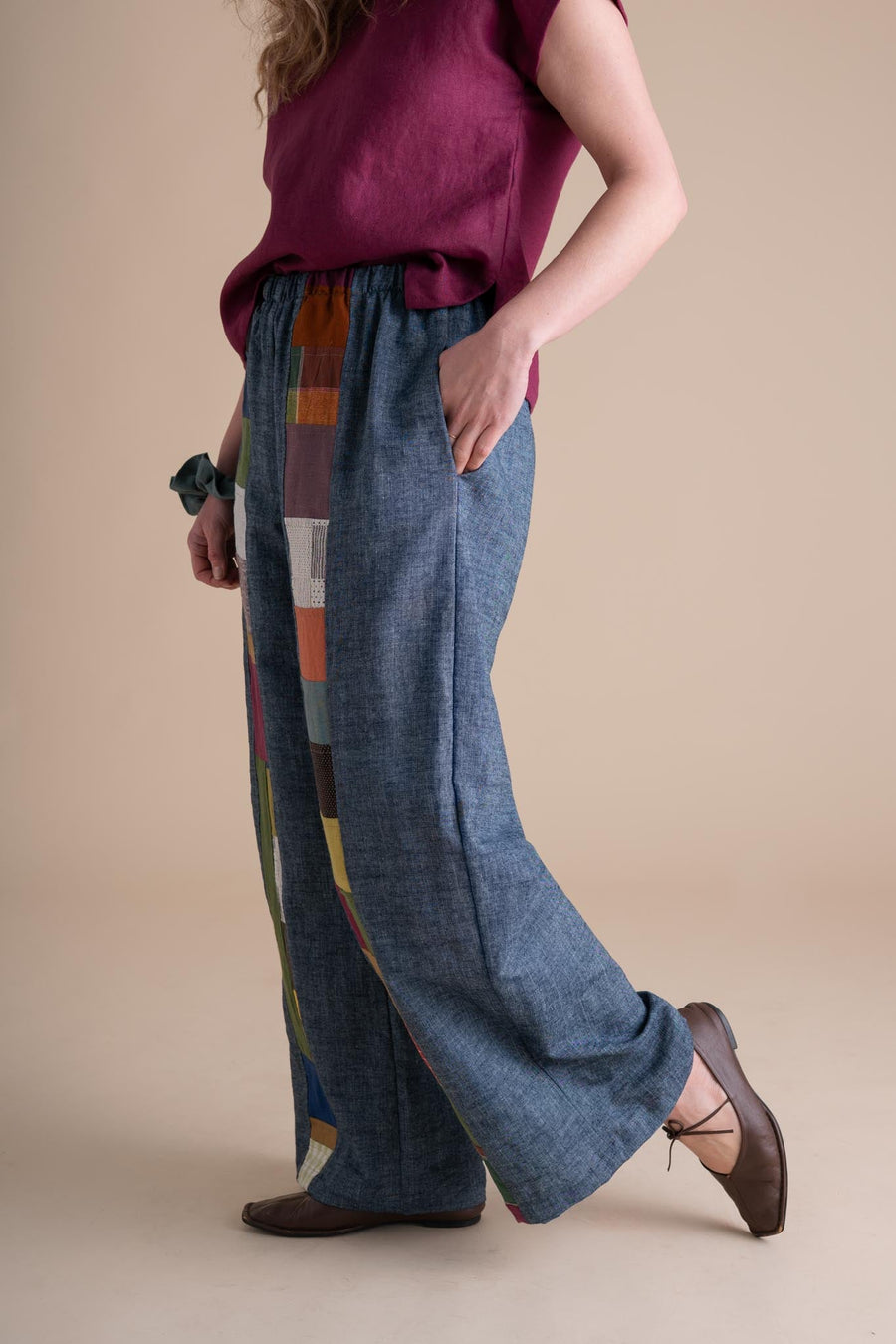 Side view of a model placing her hand in the side pocket of the relaxed-fit indigo chambray wide-leg pants.