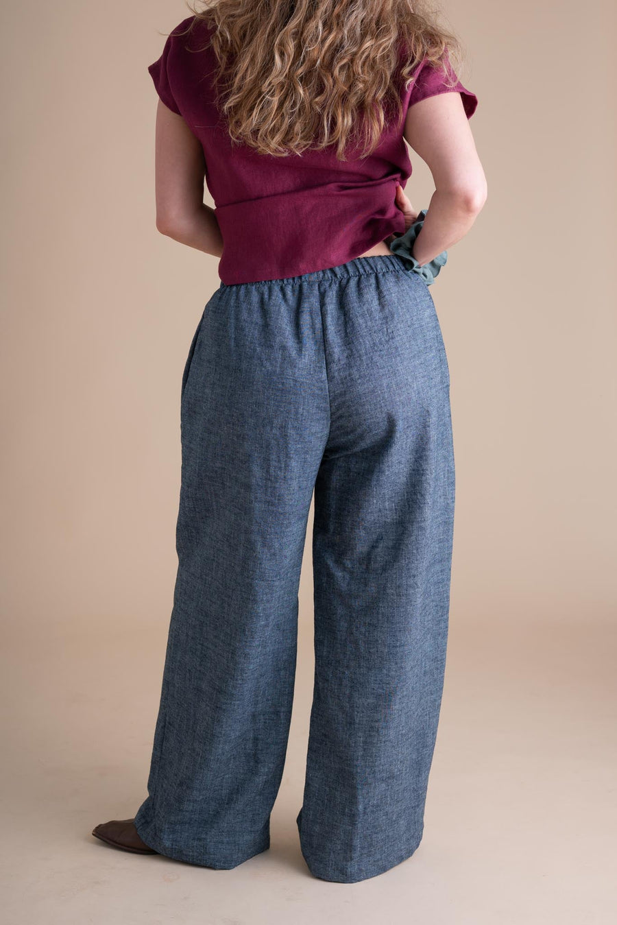 Rear view of a model wearing the high-waisted indigo chambray Joystripe Pants, highlighting the elastic waist and full coverage back.