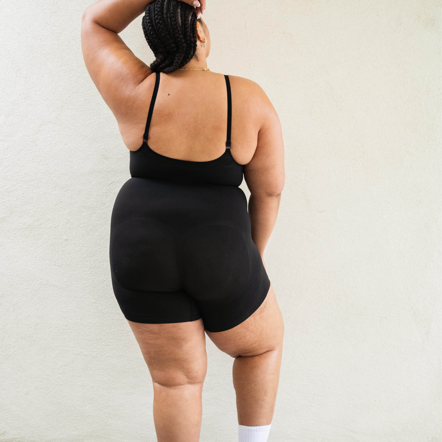 Size inclusive model in PROCLAIM Mid-Thigh Shapewear Bodysuit - bodysuit, back view