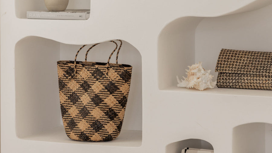 The black geometric motif variant of the handwoven clutch displayed inside a minimalist white wall shelf next to a conch shell.