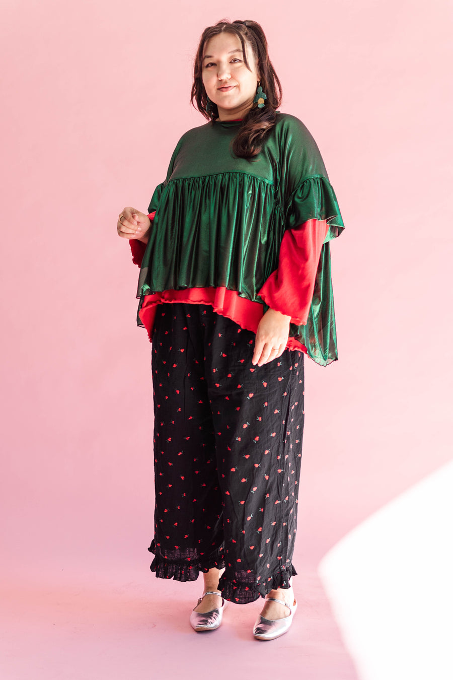 A model against a pink background wearing the voluminous Green Tinsel Mushroom Top by Nettle Studios.