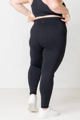 Back view close-up of a model wearing high-waisted black Superfit Hero compression ankle leggings, showing the stay-put waistband.