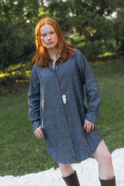 Model Bronwyn wearing the Conscious Clothing Aurelia Dress in Indigo Chambray posing outdoors in a natural garden setting.