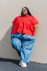Outdoor full-length shot of model Keda leaning against a wall in the light floral chambray ruffle pants.