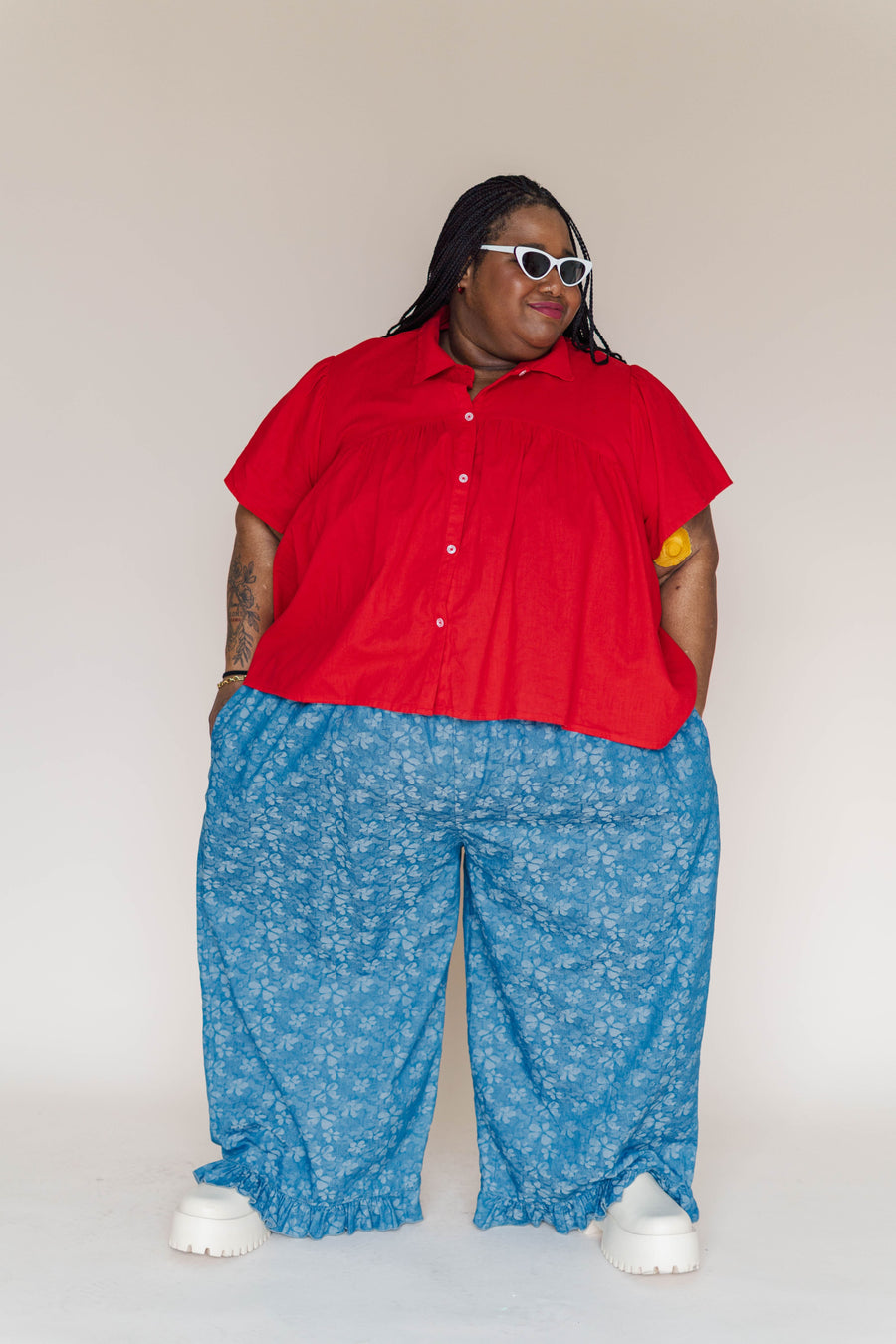 Front studio shot of model Keda posing in the relaxed floral chambray pants with hands in side pockets.