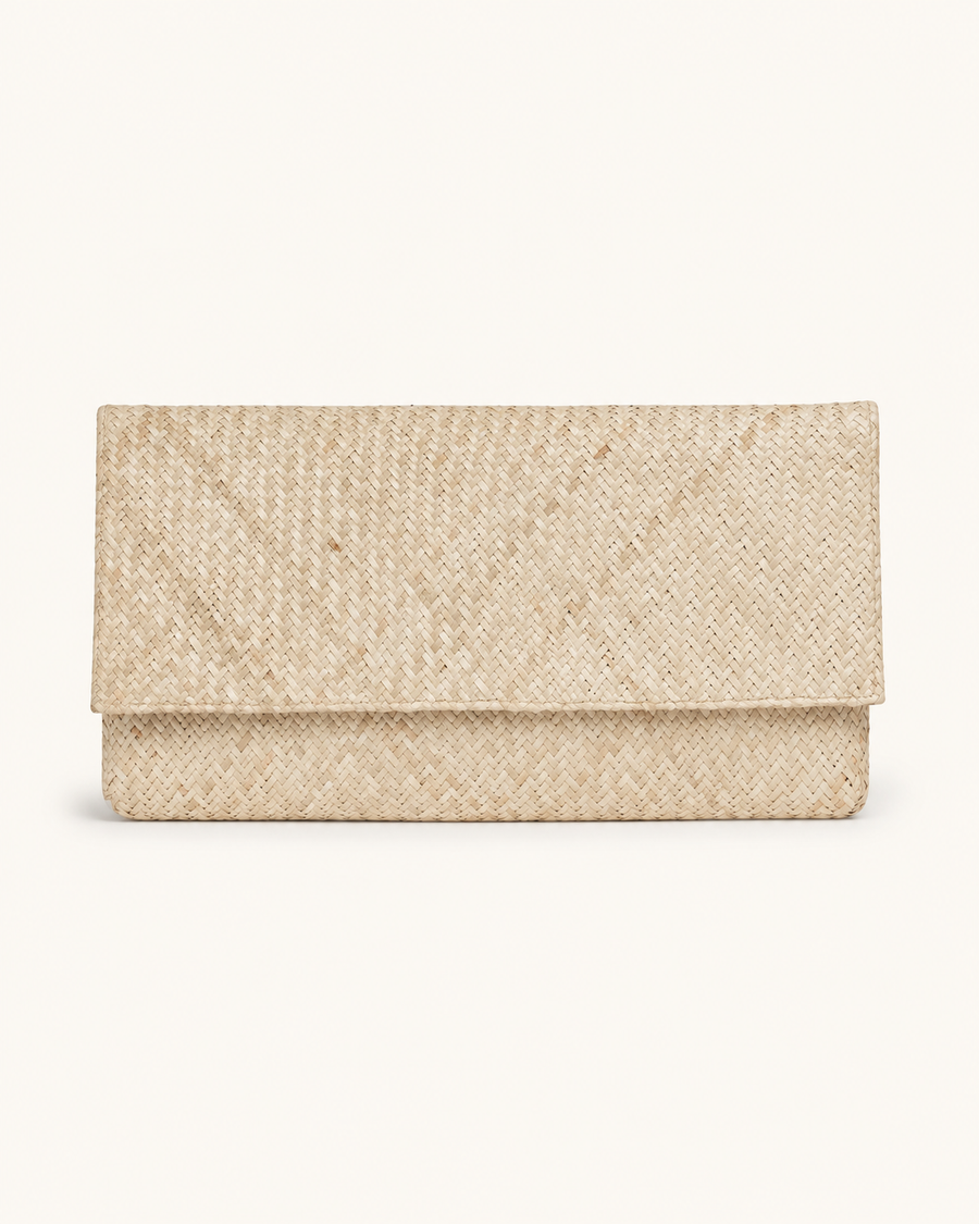 A straight-on studio shot of the Village Thrive woven clutch in the natural straw color variant, highlighting the clean envelope silhouette.