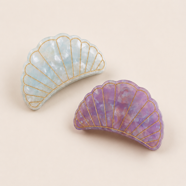Flat lay view of the Village Thrive Shell Hair Clips in pink and Blue marbled recycled acetate, featuring decorative gold-lined shell ridge details.