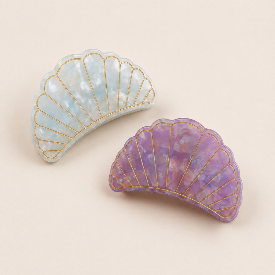 Flat lay view of the Village Thrive Shell Hair Clips in pink and Blue marbled recycled acetate, featuring decorative gold-lined shell ridge details.