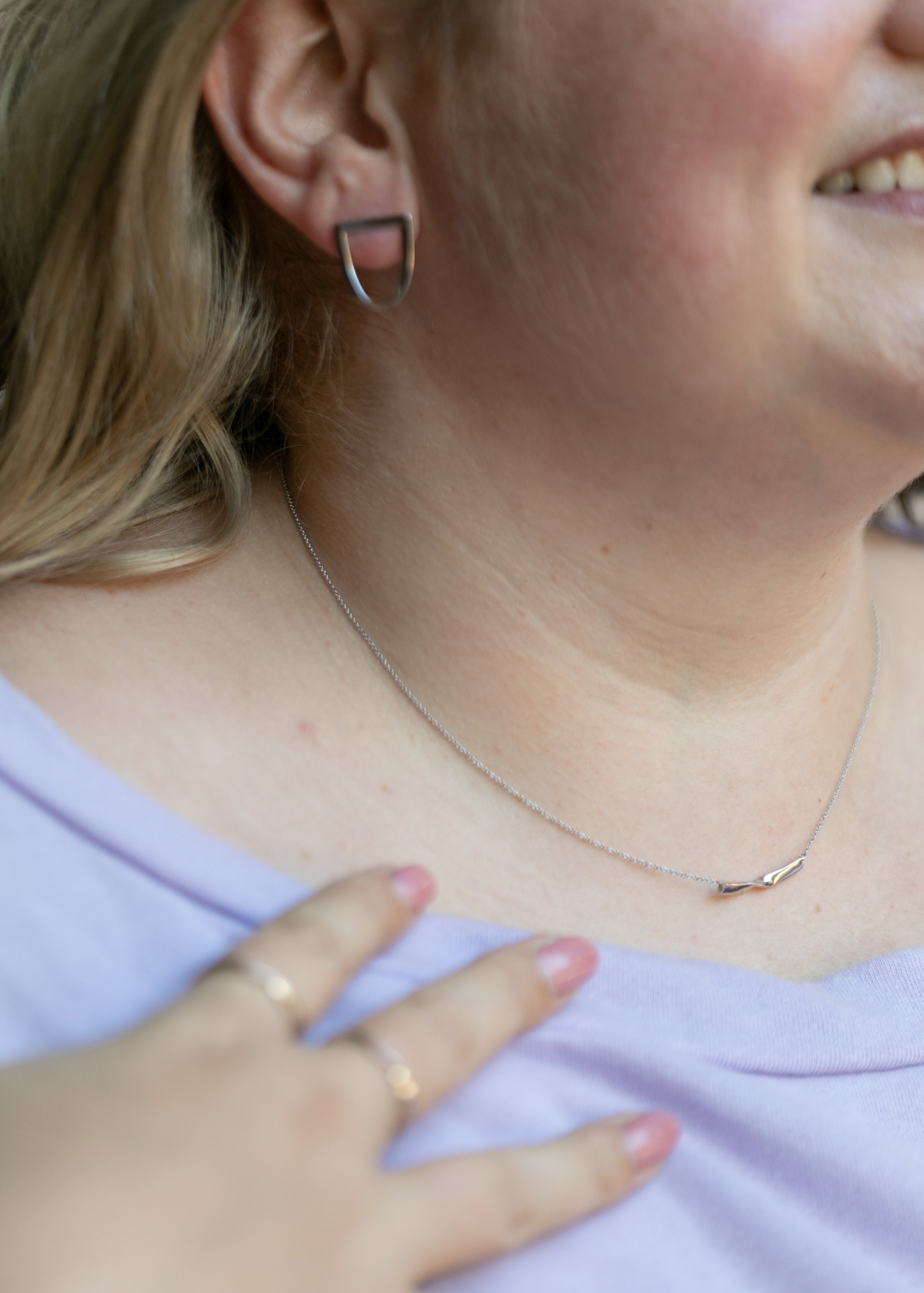 a details shot featuring a plus size blonde woman wearing the twist earring and twist necklace in silver. #color_silver