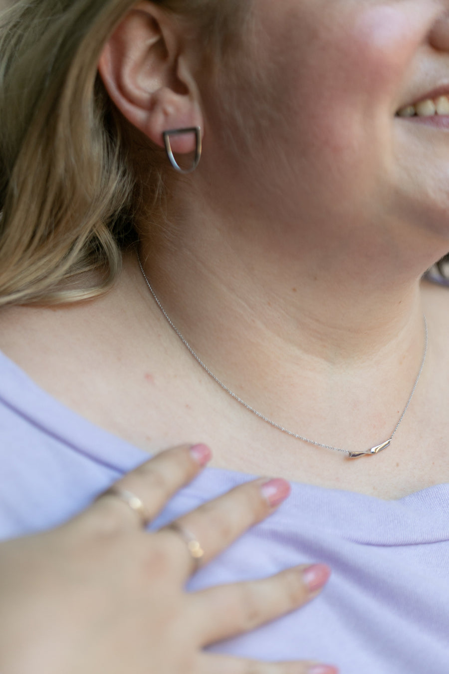 Chouette Designs a details shot featuring a plus size blonde woman wearing the twist earring and twist necklace in silver