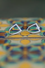 Chouette Designs a pair of silver twist earrings sit atop a colorful Spanish style tile