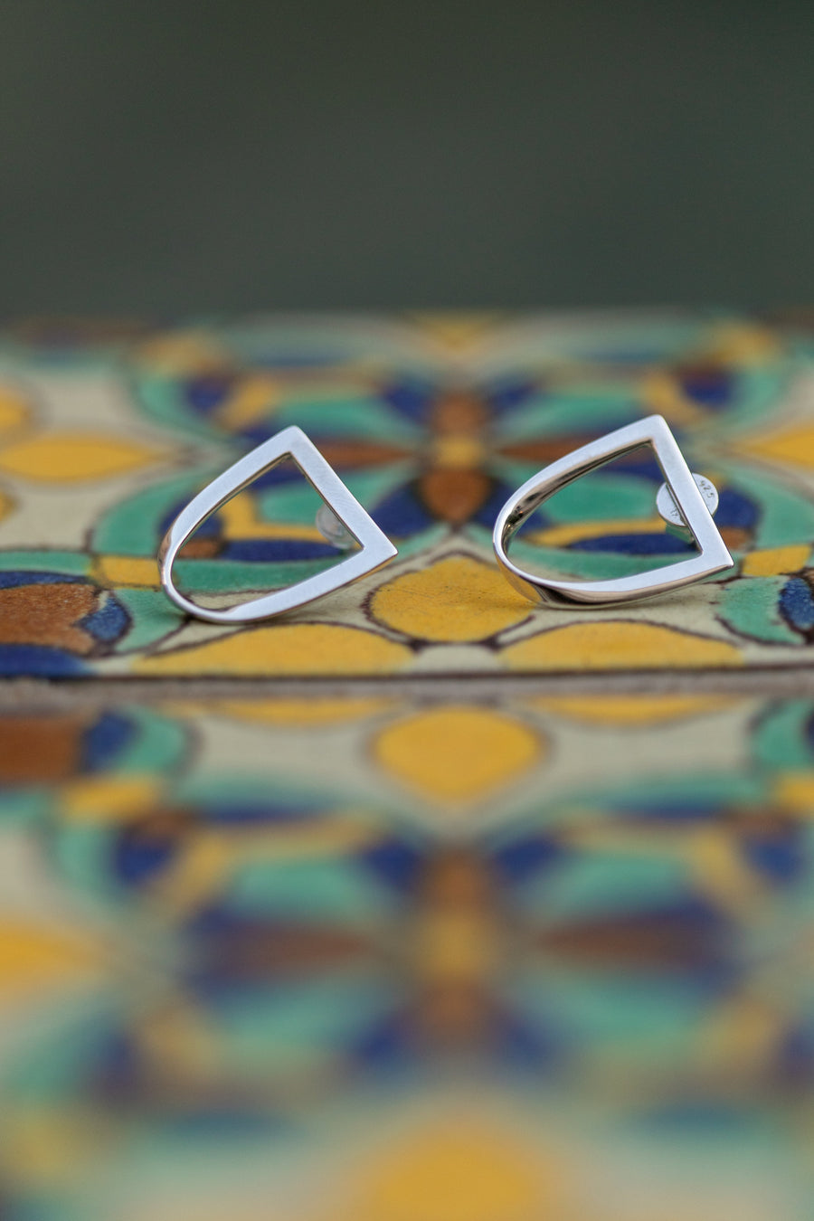 Chouette Designs a pair of silver twist earrings sit atop a colorful Spanish style tile