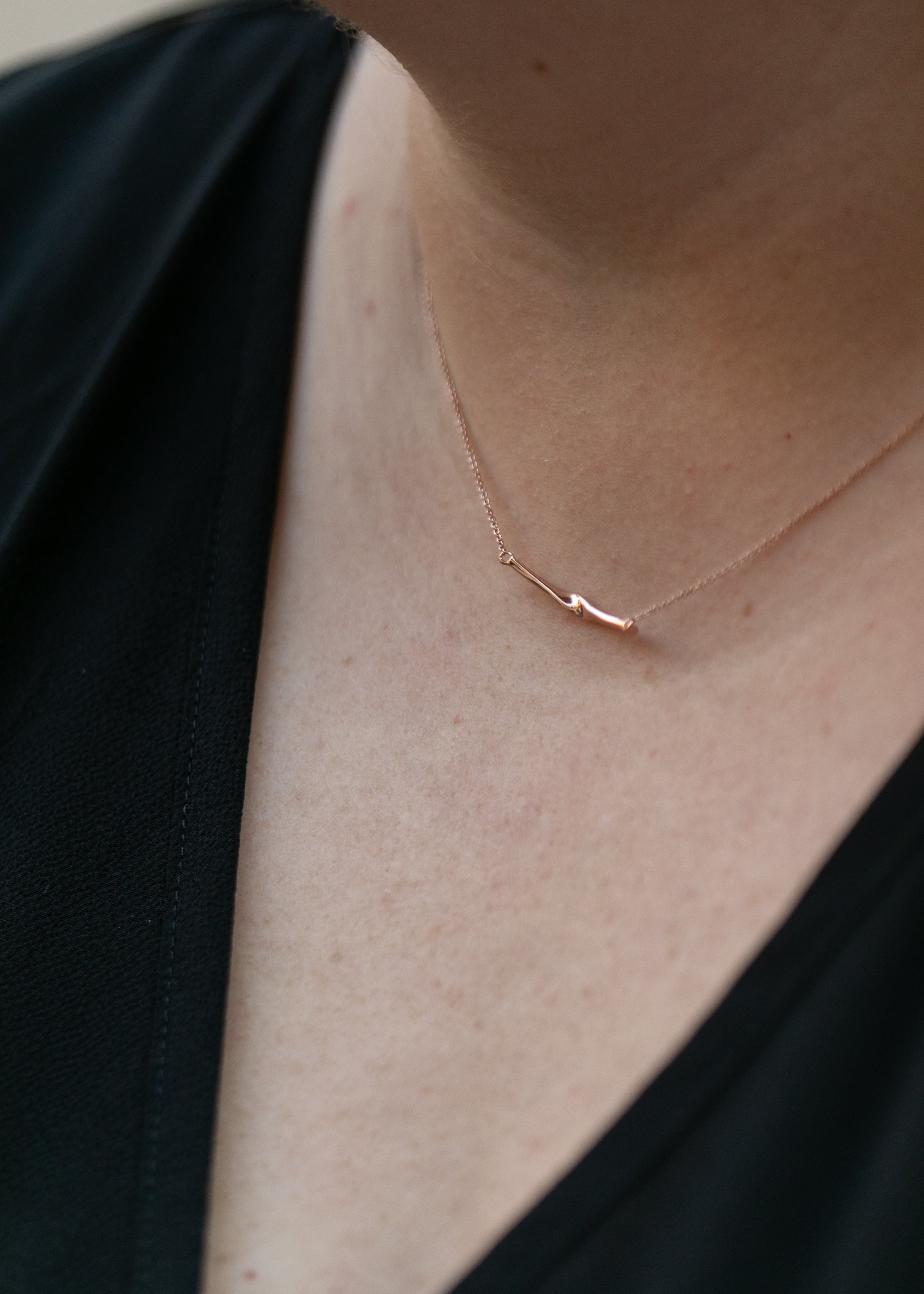 a close up of a woman's neck wearing a rose gold twist necklace. #color_rose-gold